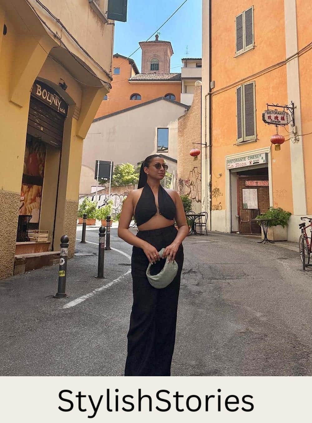 Woman wearing a long black skirt and crop top with brown sandals in Italy.