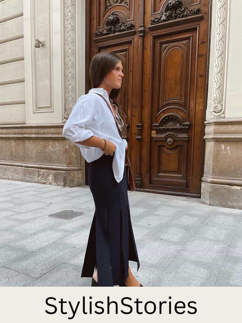 Woman wearing along black skirt, black platform sandals and an oversized white, linen button down.