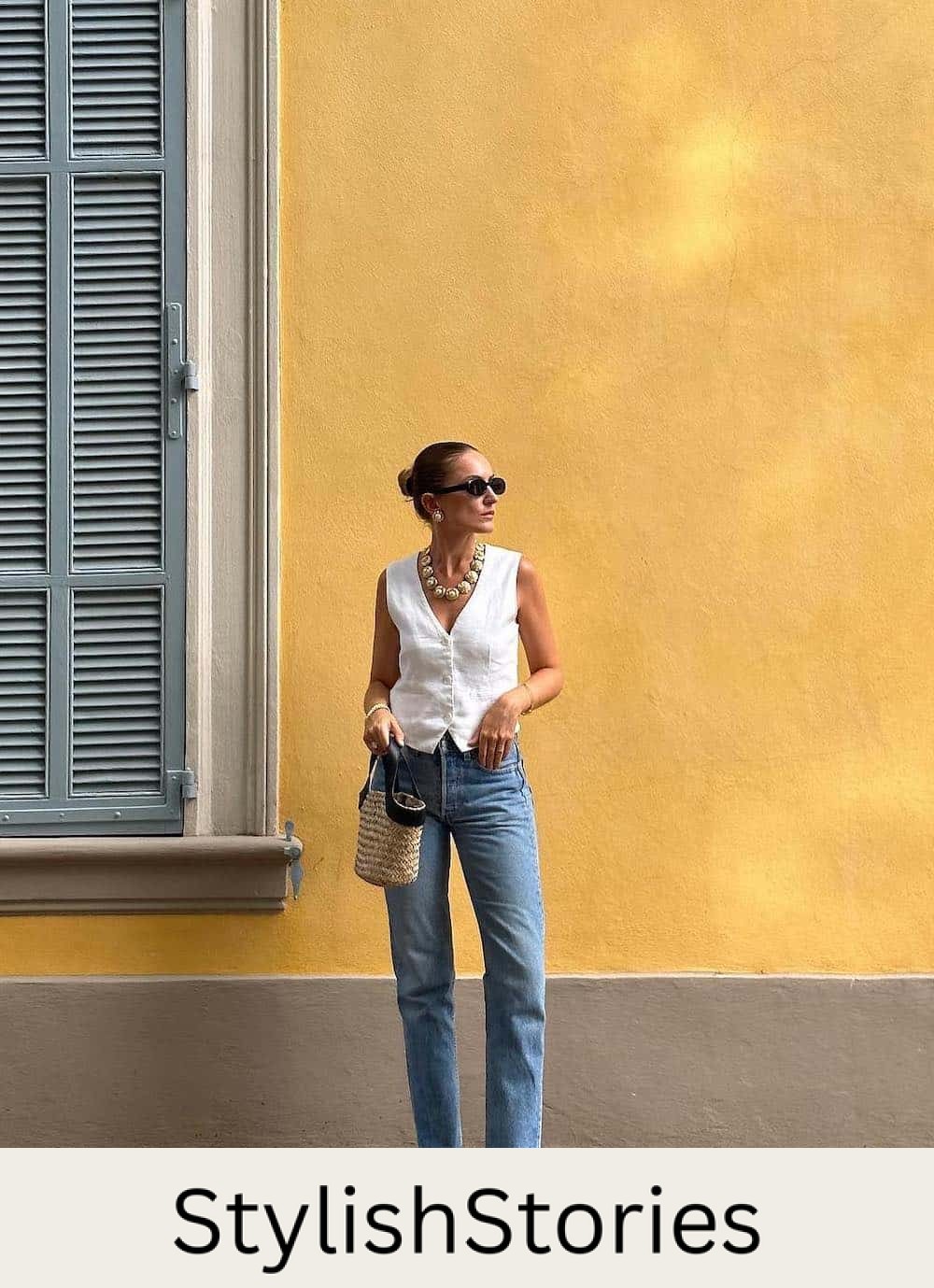 Woman wearing straight jeans, a white linen best and black loafers.