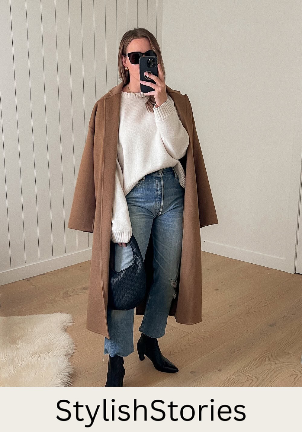 Christal wearing jeans, black booties, a white sweater and a camel colored long coat.