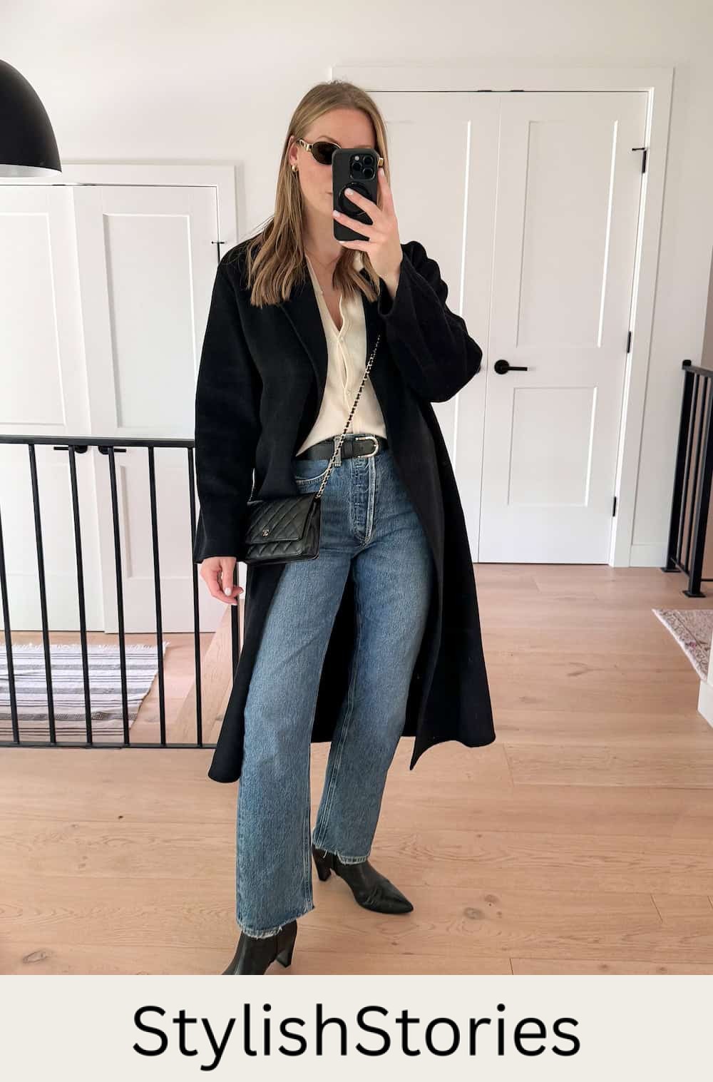 Christal wearing jeans, black booties, a button down and a long coat.