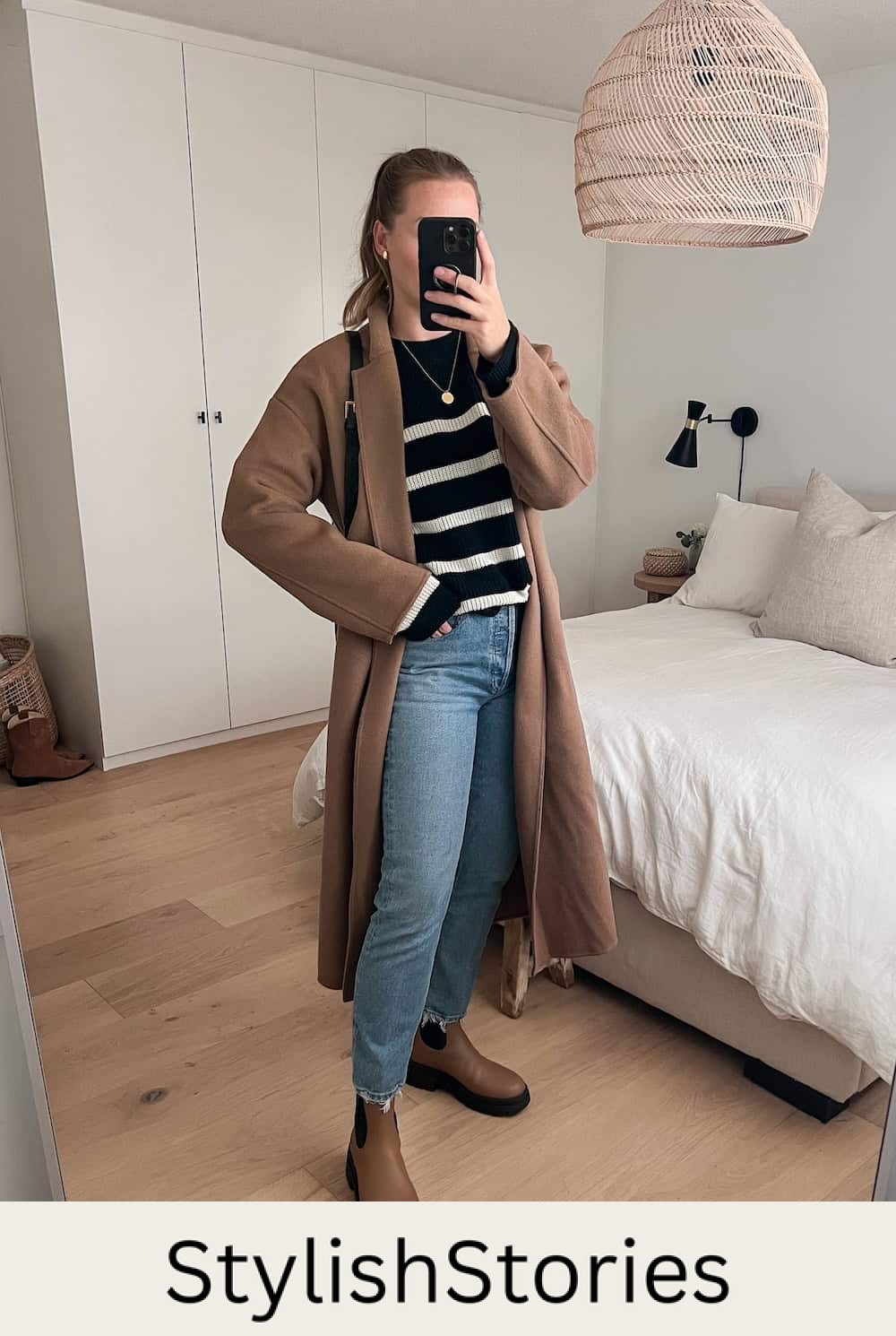 Christal wearing a black and white striped sweater with jeans, Chelsea boots and a long coat.
