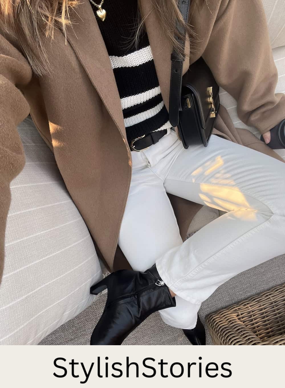 Christal wearing white jeans, a sweater, booties and a long coat.