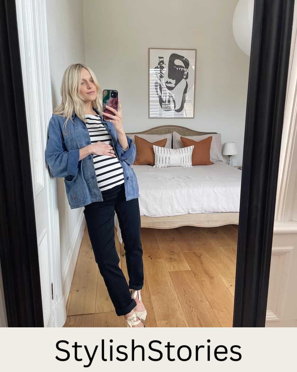 Pregnant woman wearing a denim jacket over a striped t-shirt with black jeans 
