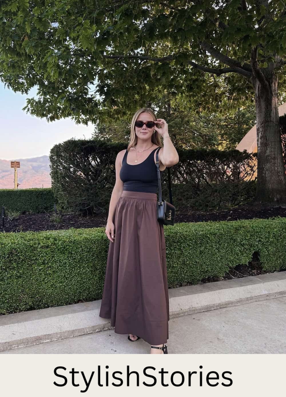 Christal wearing a brown maxi skirt with a black tank top and heeled sandals.