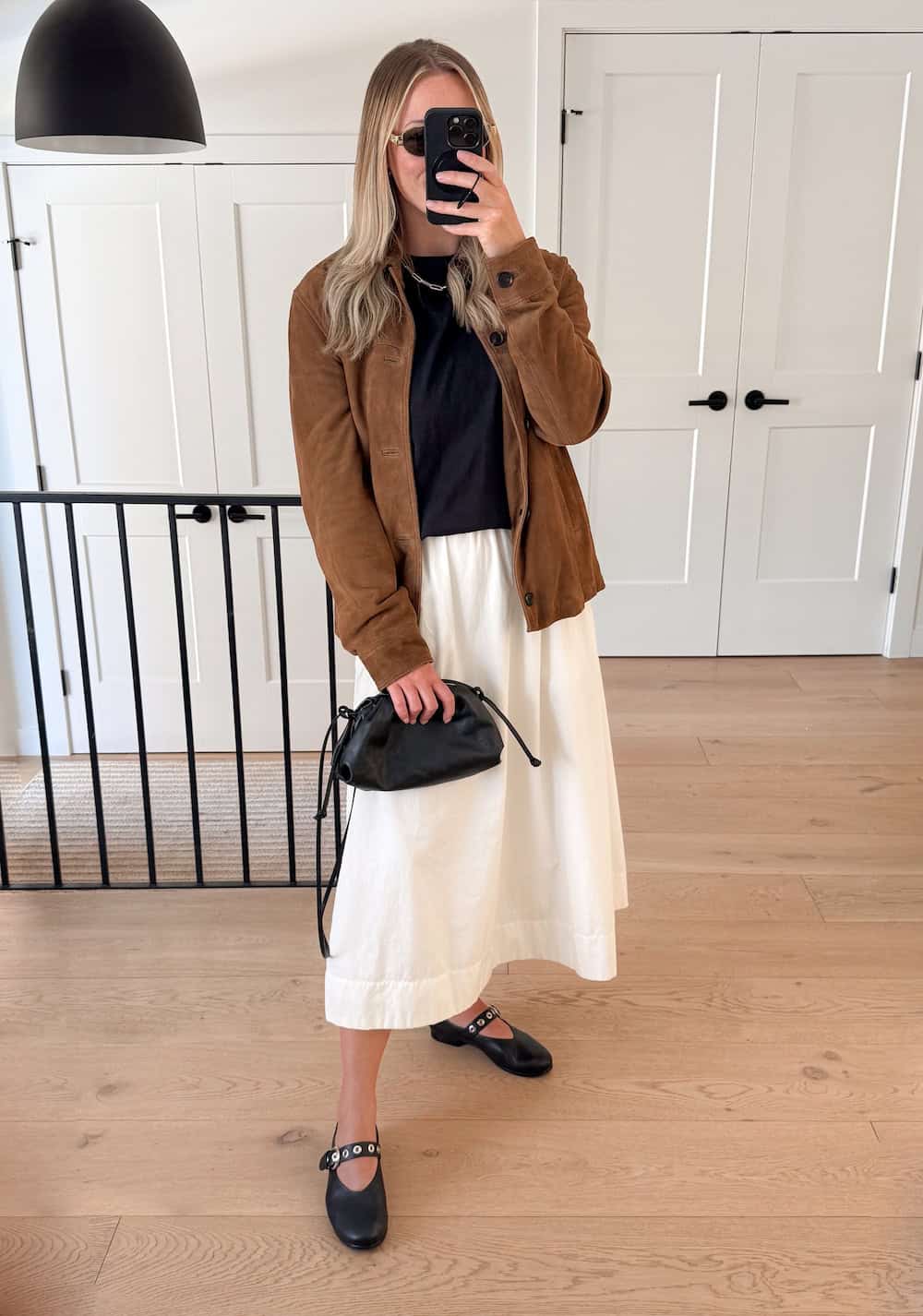 Christal wearing a white maxi skirt with a black top and brown jacket.