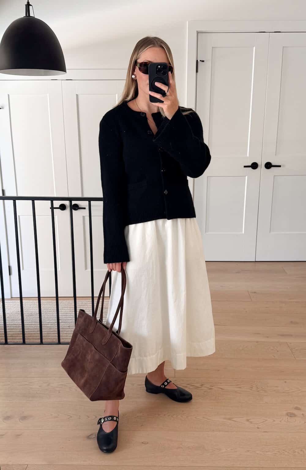 Christal wearing a white maxi skirt with a black sweater and black flats.