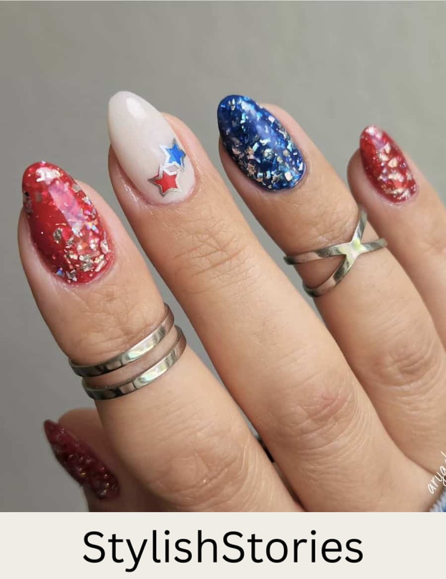 short almond nails with red and blue polish with chunky silver glitter and a milky white accent nail with stars