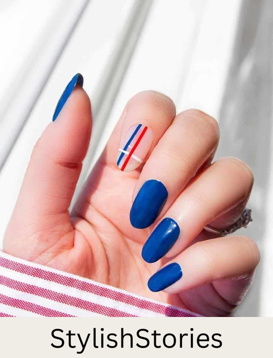 long round blue nails with a nude accent nail featuring red, white, and blue strips
