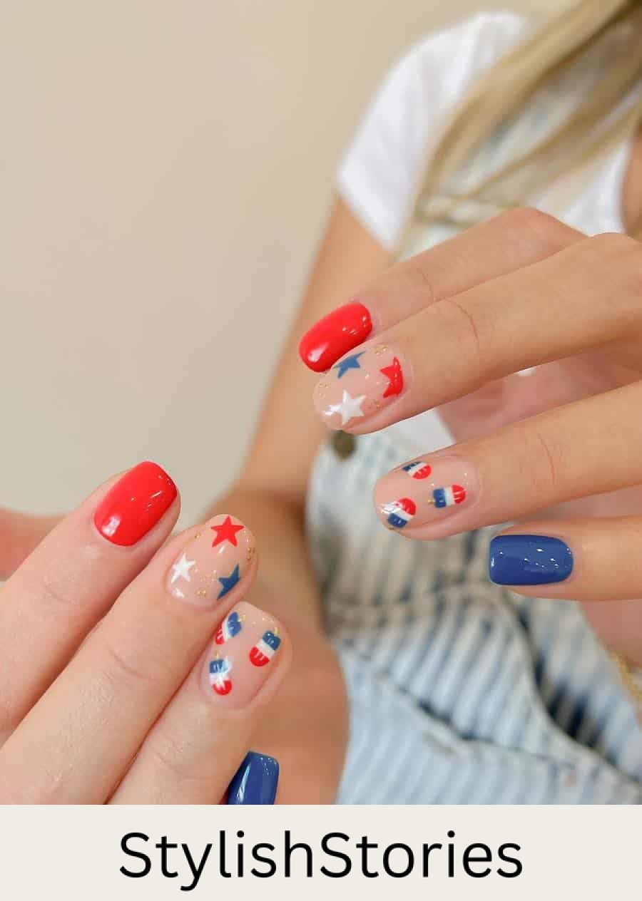 short squoval nails painted with red and blue polish and nude accent nails with stars and popsicle nail art