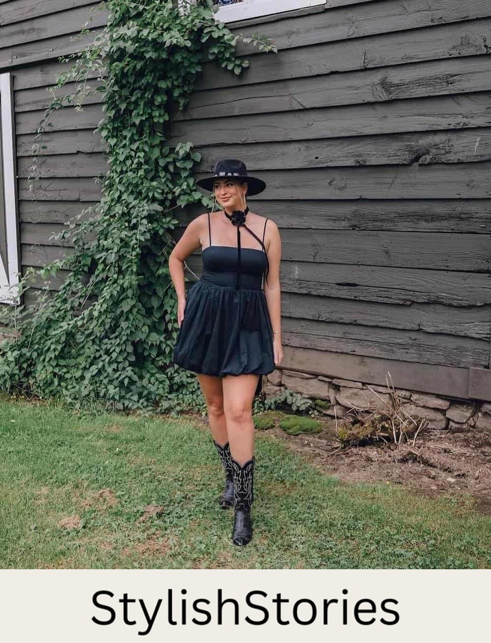 A woman wearing a black mini dress with black cowboy boots and a wide-brimmed black hat
