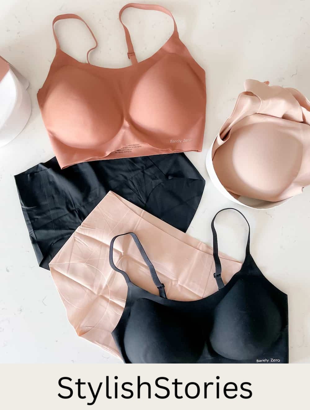 image of three NEIWAI Barely Zero bras on a marble surface in black, and dark nude pink, and two pairs of Barely Zero underwear in black and light pink