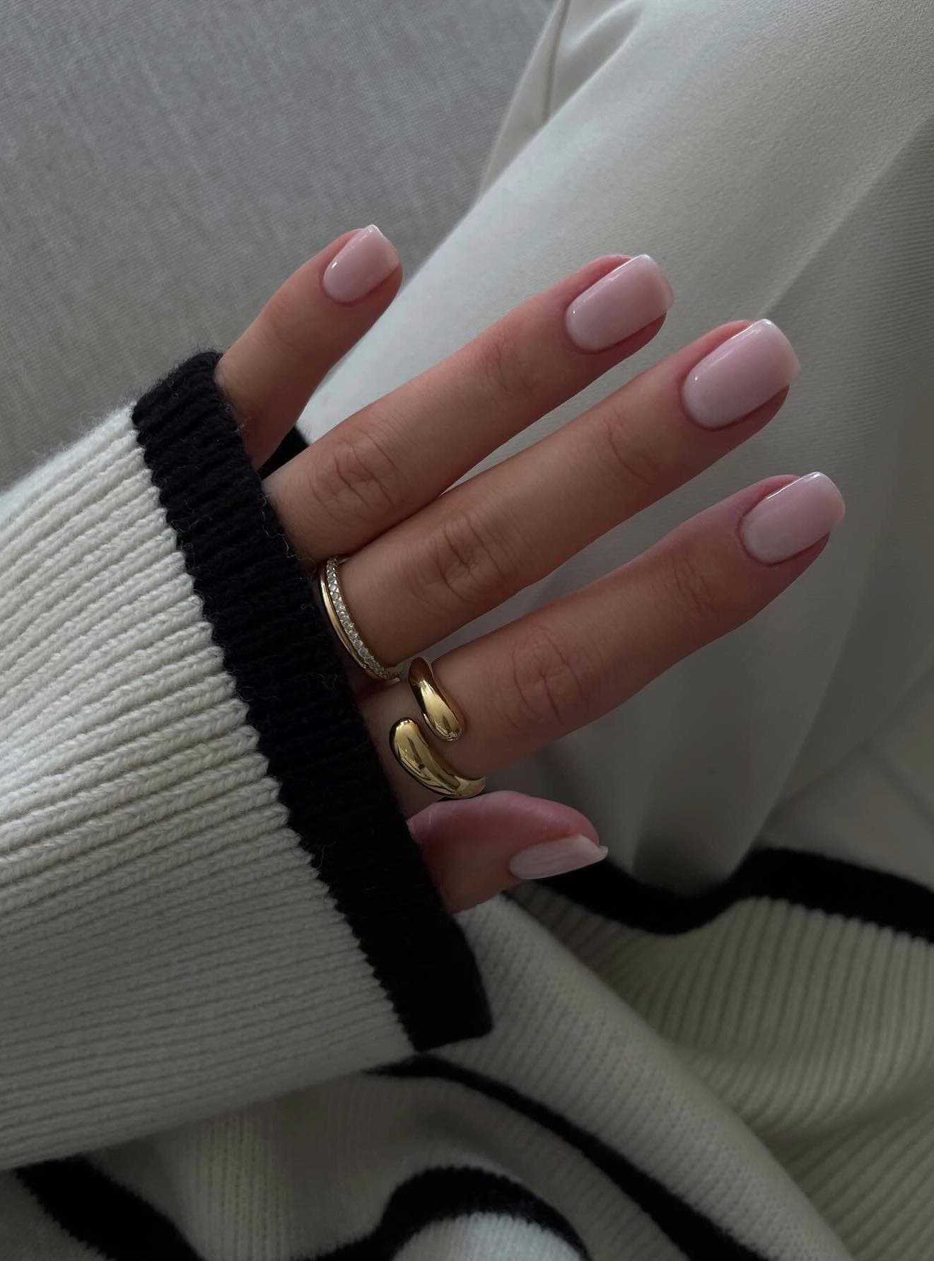 A hand with short milky pink nails