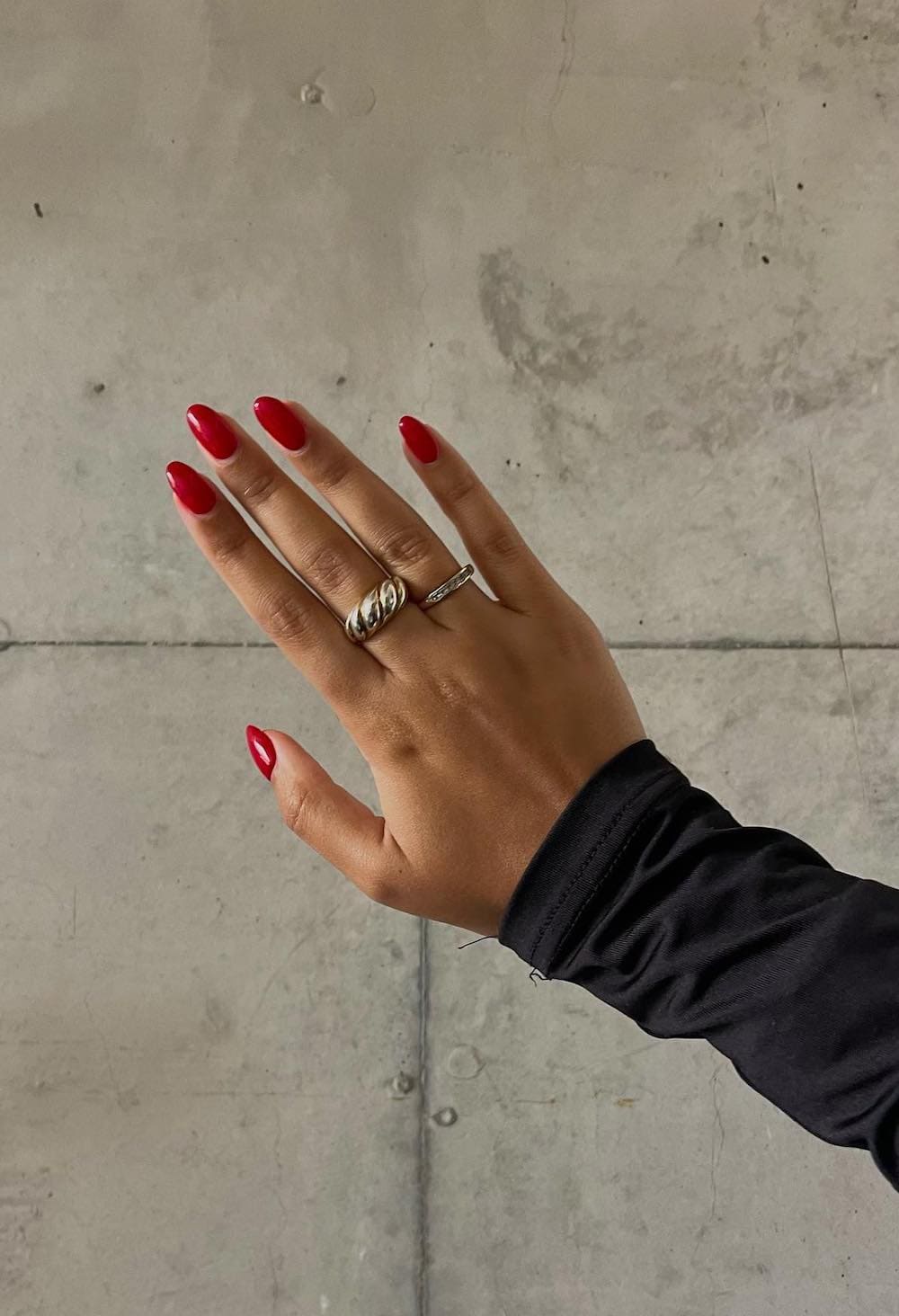 A hand with short round nails painted with a cherry red polish