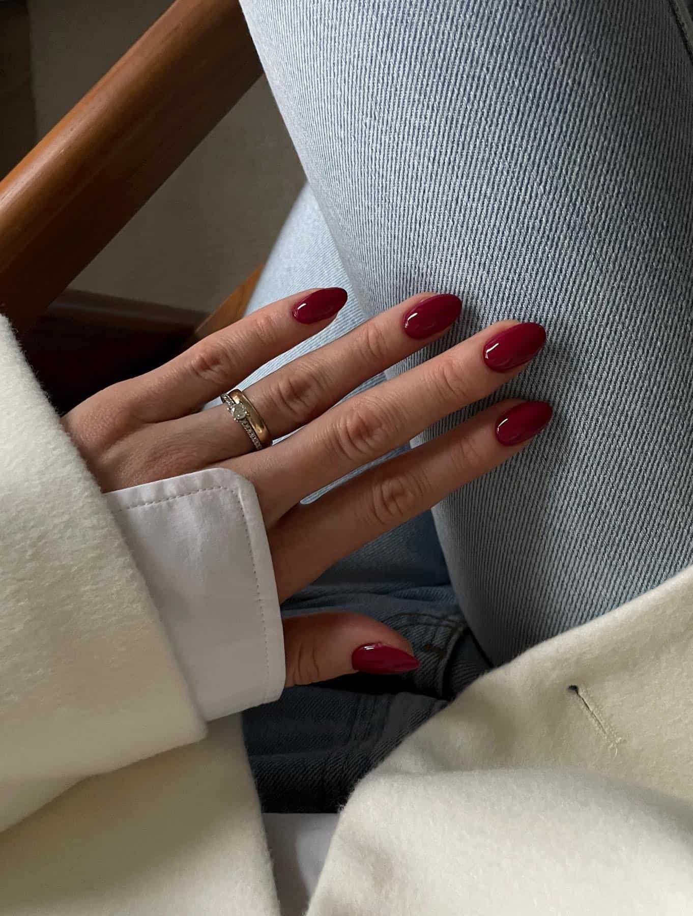 A hand with short round nails painted a dark red color