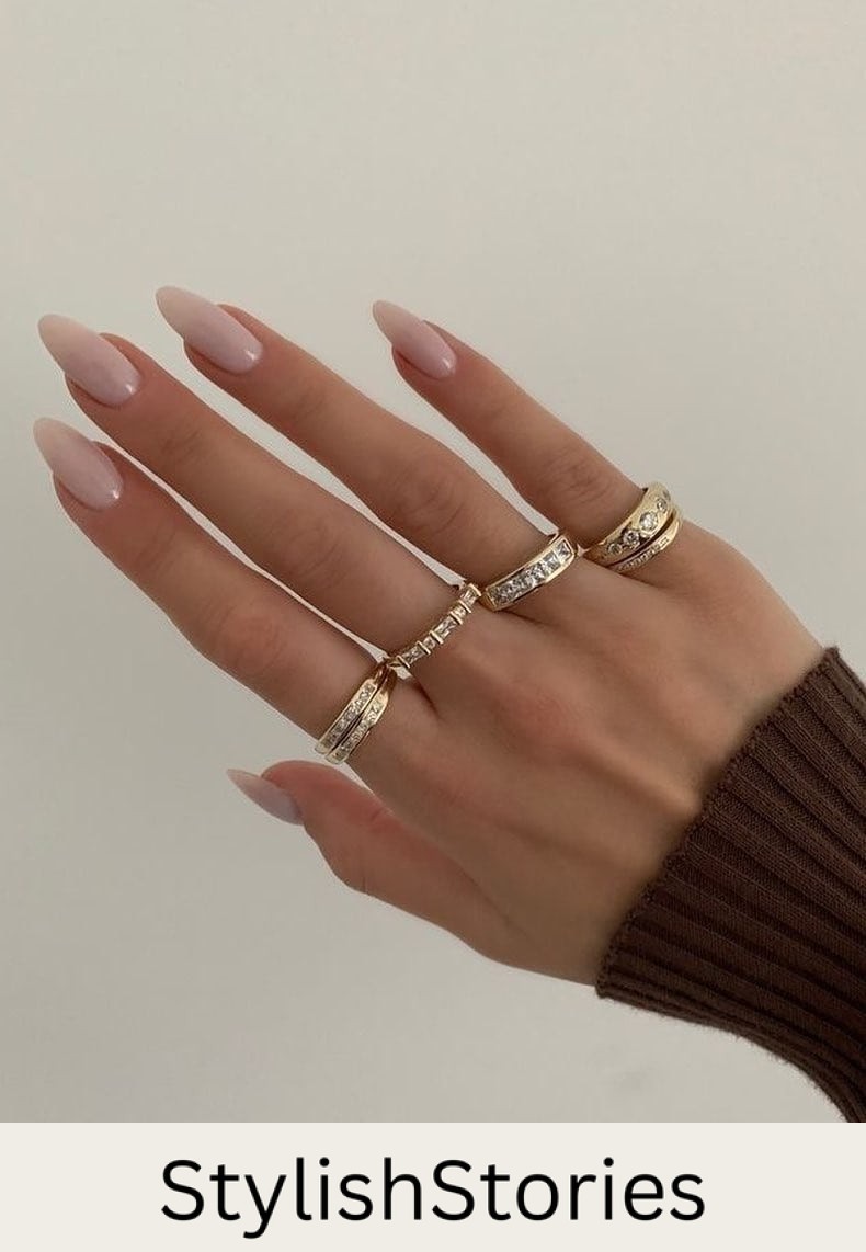 A hand with medium almond nails painted a soft milky pink