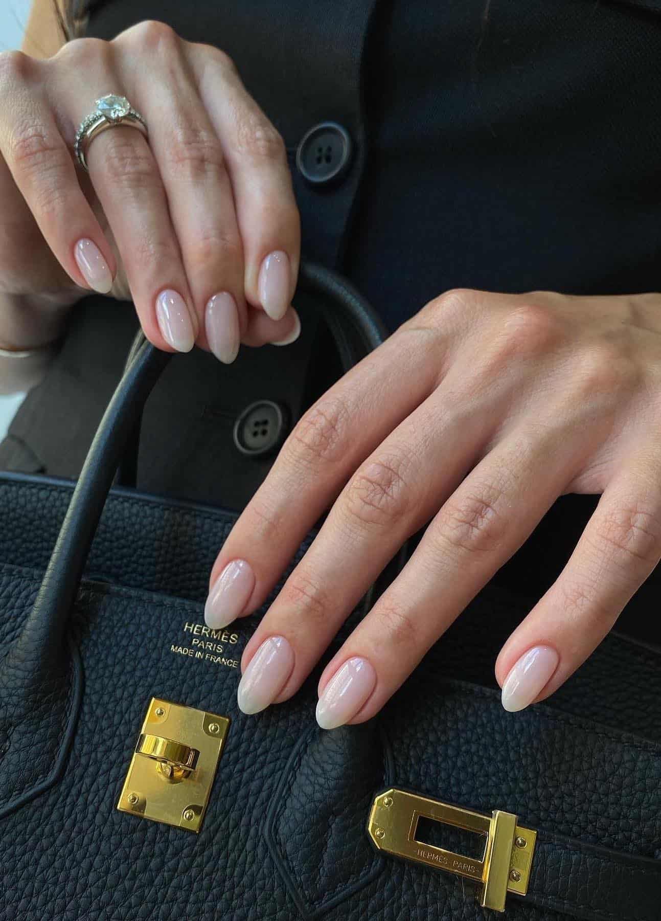 A hand with short almond nails painted a milky white