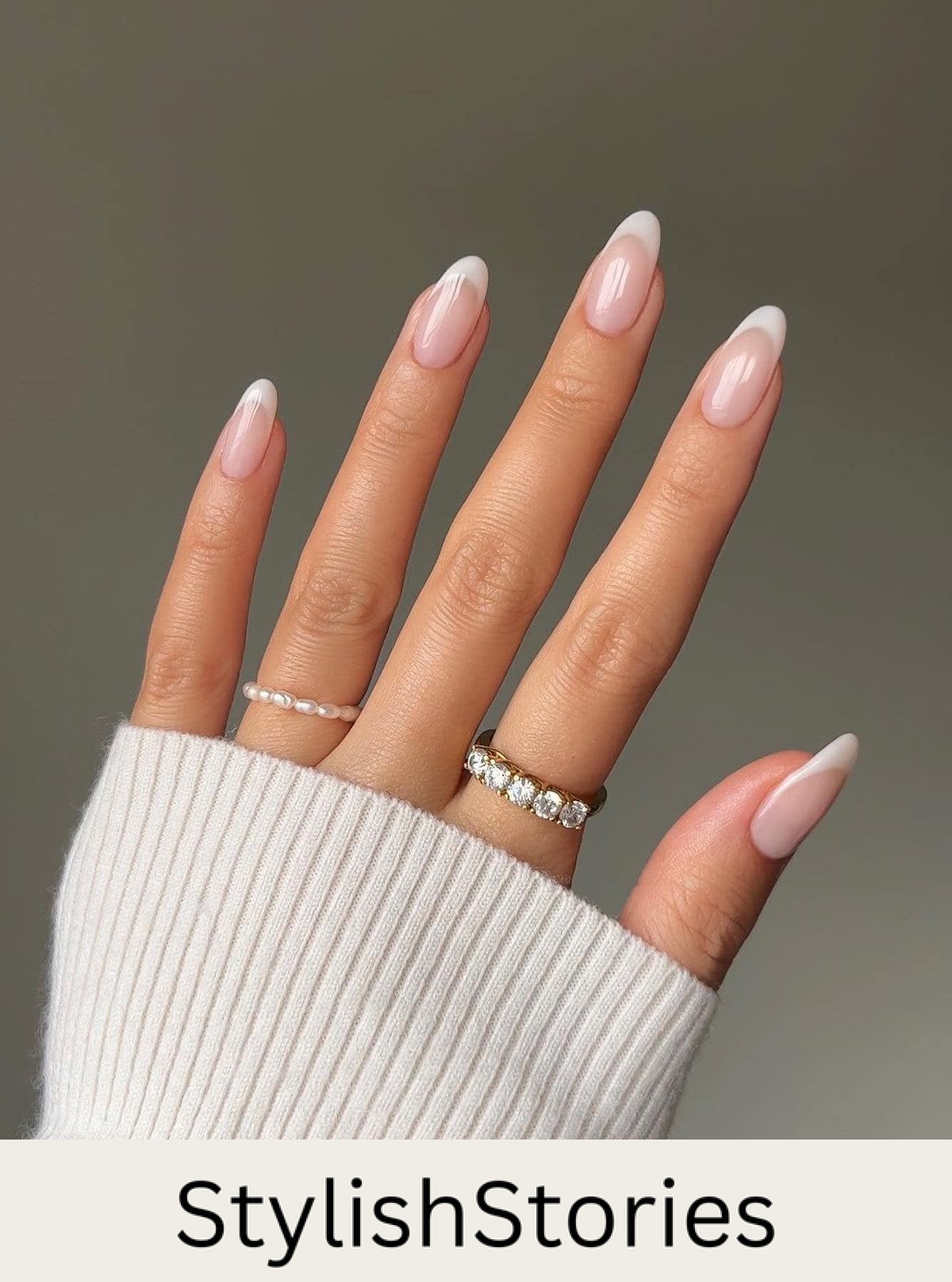 A hand with medium glossy almond nails with white tips