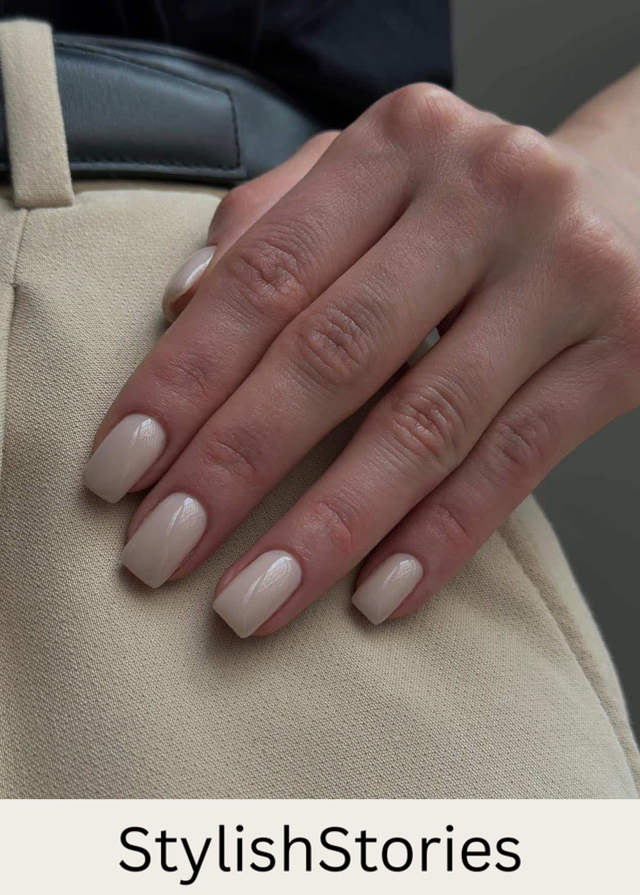 A hand with short square nails painted a glossy soft beige