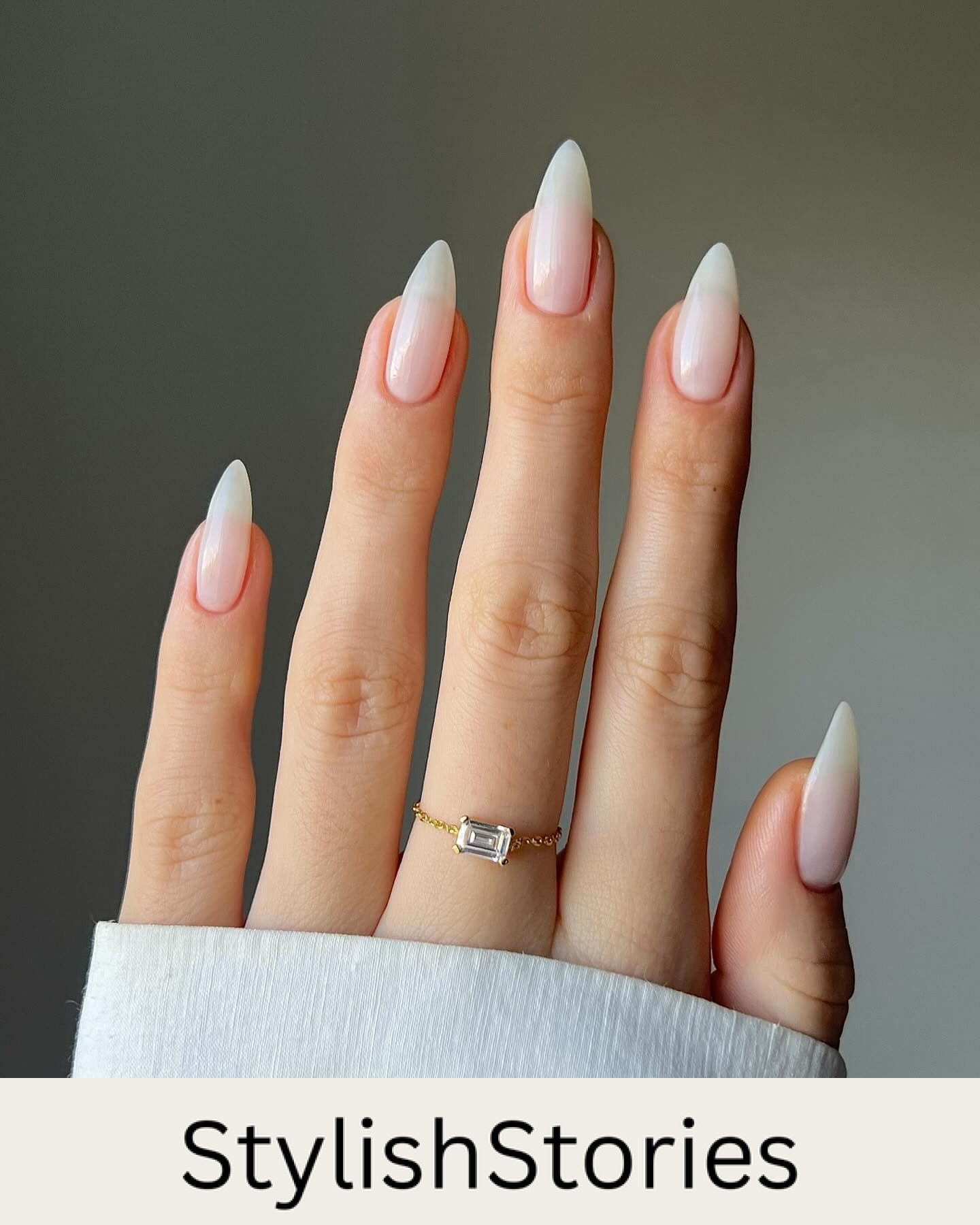 A hand with medium almond nails painted a milky white