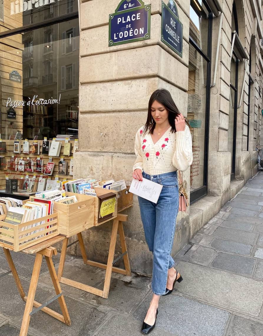 french woman wearing a knit embroidered cardigan, jeans, and black slingback pumps