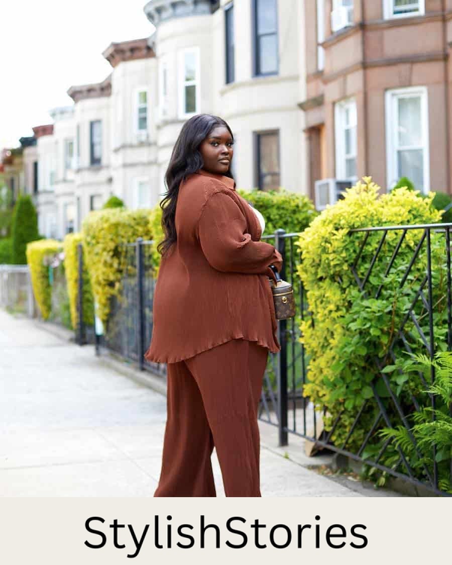 A woman wearing a matching set with long brown pants and a brown button-up with a white top underneath