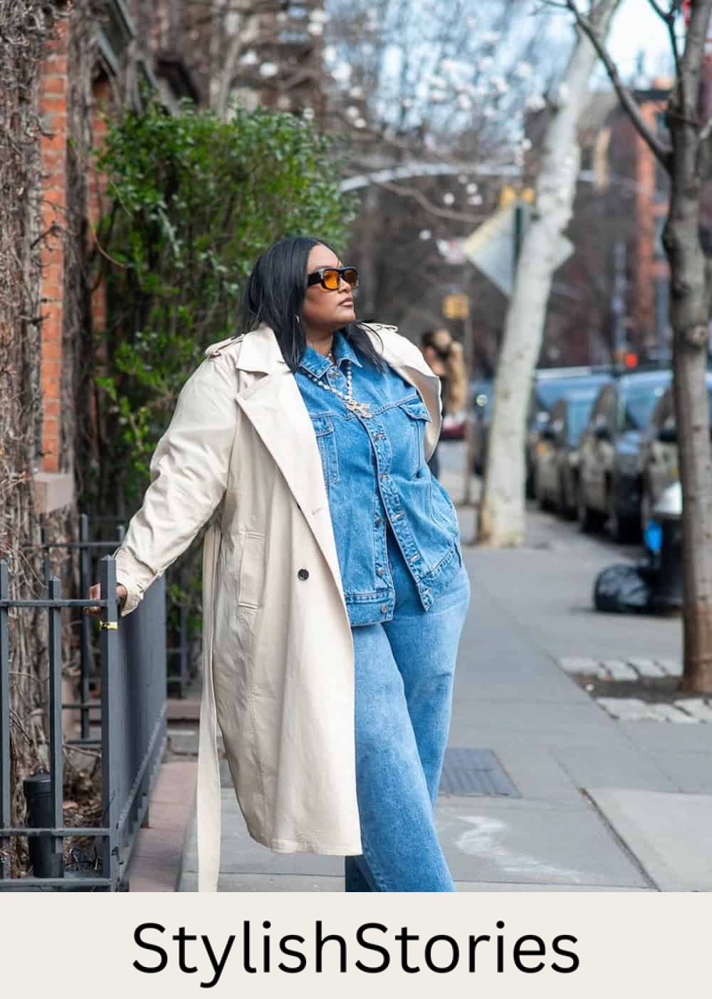 a woman wearing a plus size thanksgiving outfit featuring a denim set and an ivory trench coat with snakeskin loafers