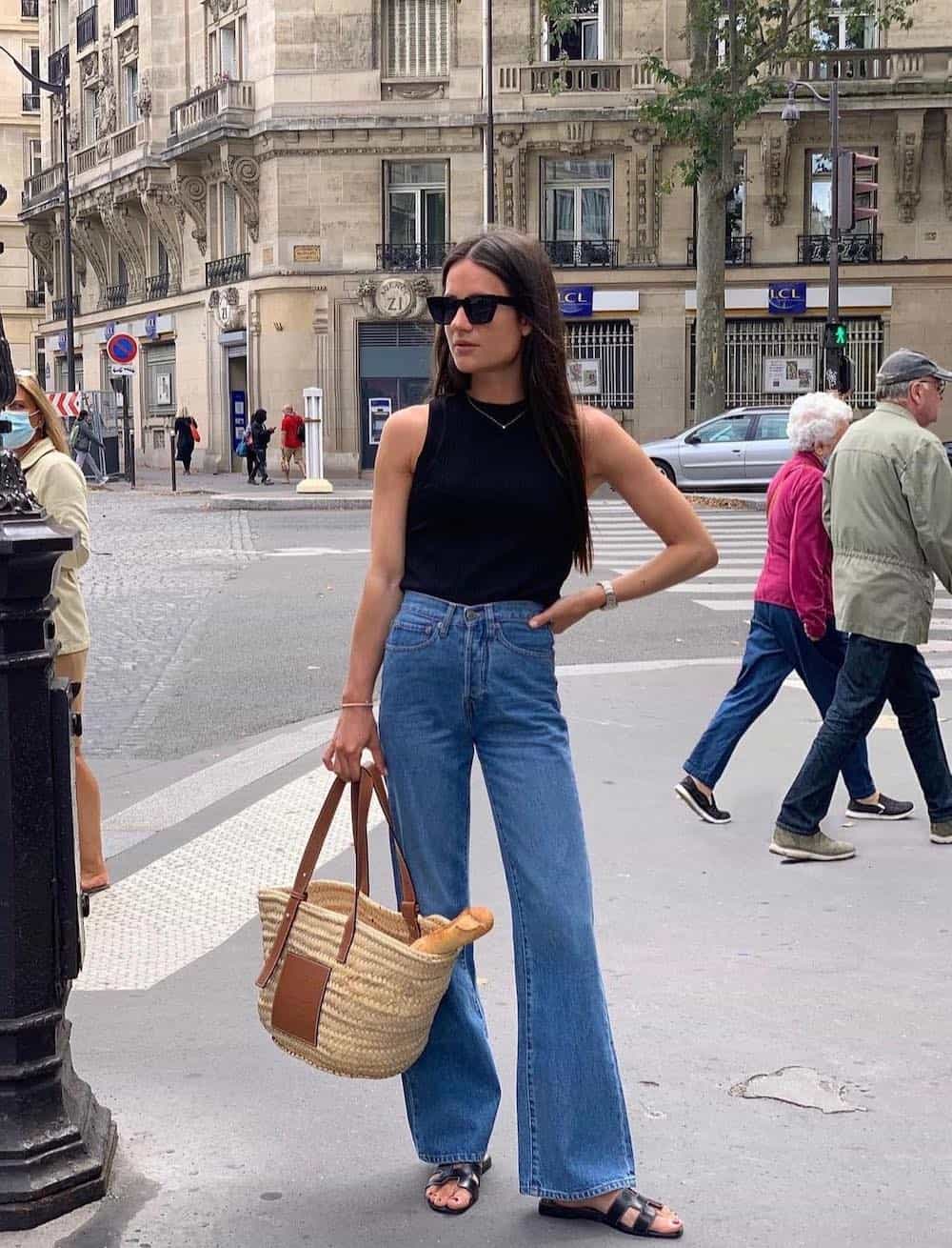 woman wearing a black tank top with full-length flared blue jeans and black flat sandals