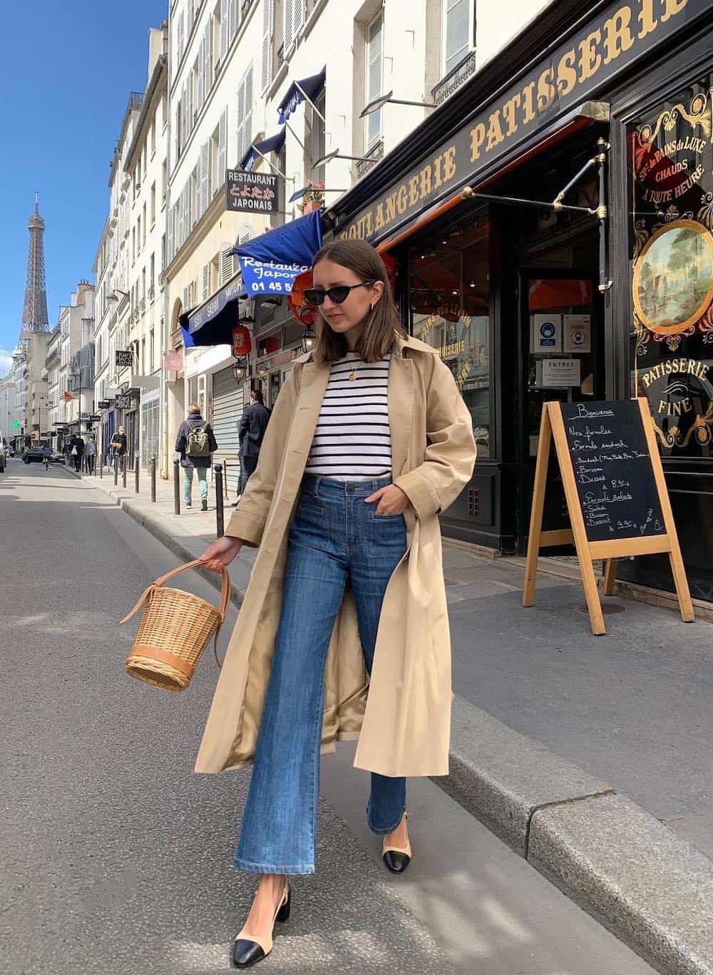 woman wearing a trench coat over a striped top and flared jeans with nude slingback pumps