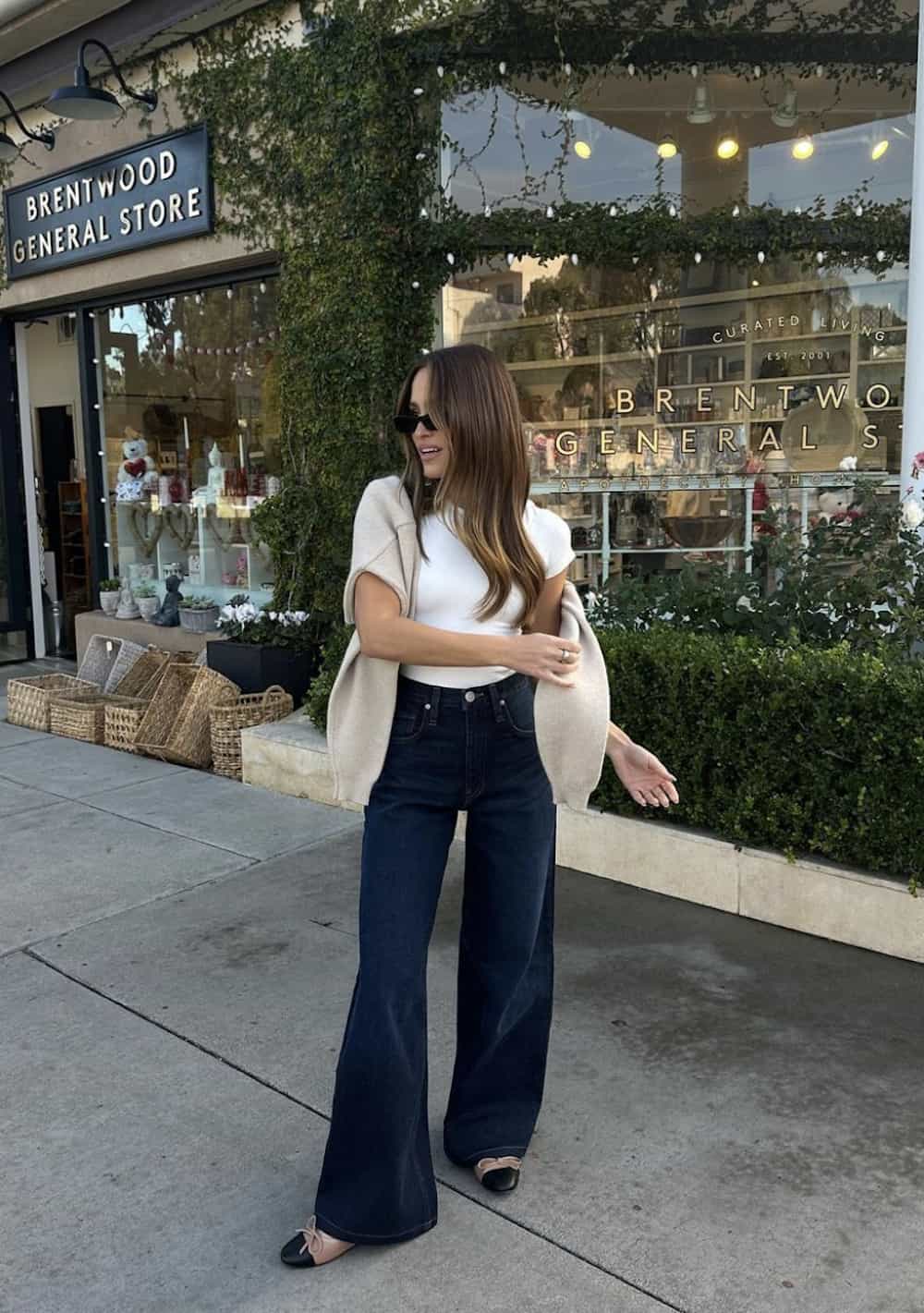 woman wearing a white t-shirt with loose-fit flared jeans and cap-toe ballet flats