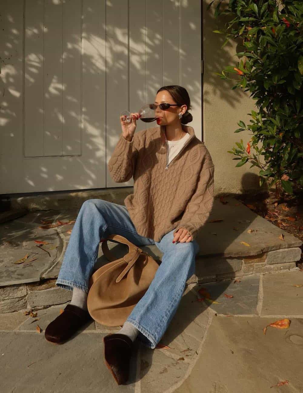 woman wearing a half-zip sweater with flared blue jeans and pony hair clogs