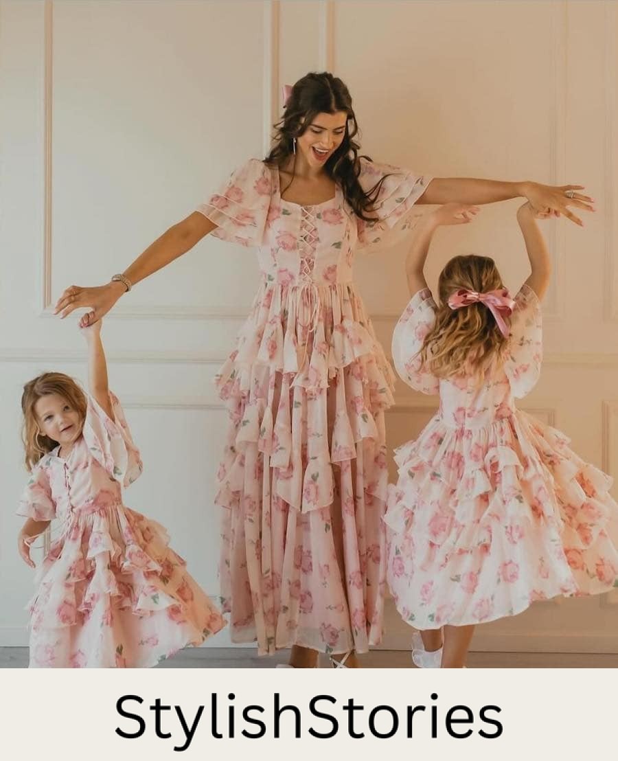 A spring family photo with a mom and her two daughters wearing matching dresses featuring a tiered ruffled skirt, pink floral print, and a lace up front
