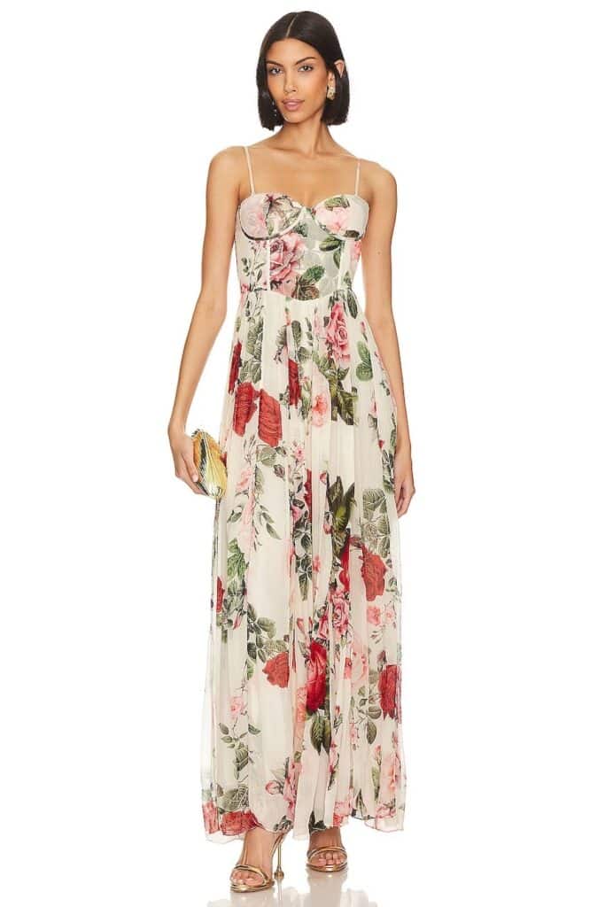 A woman wearing a white dress with a red rose print, a pleated skirt, and a fitted corset bodice