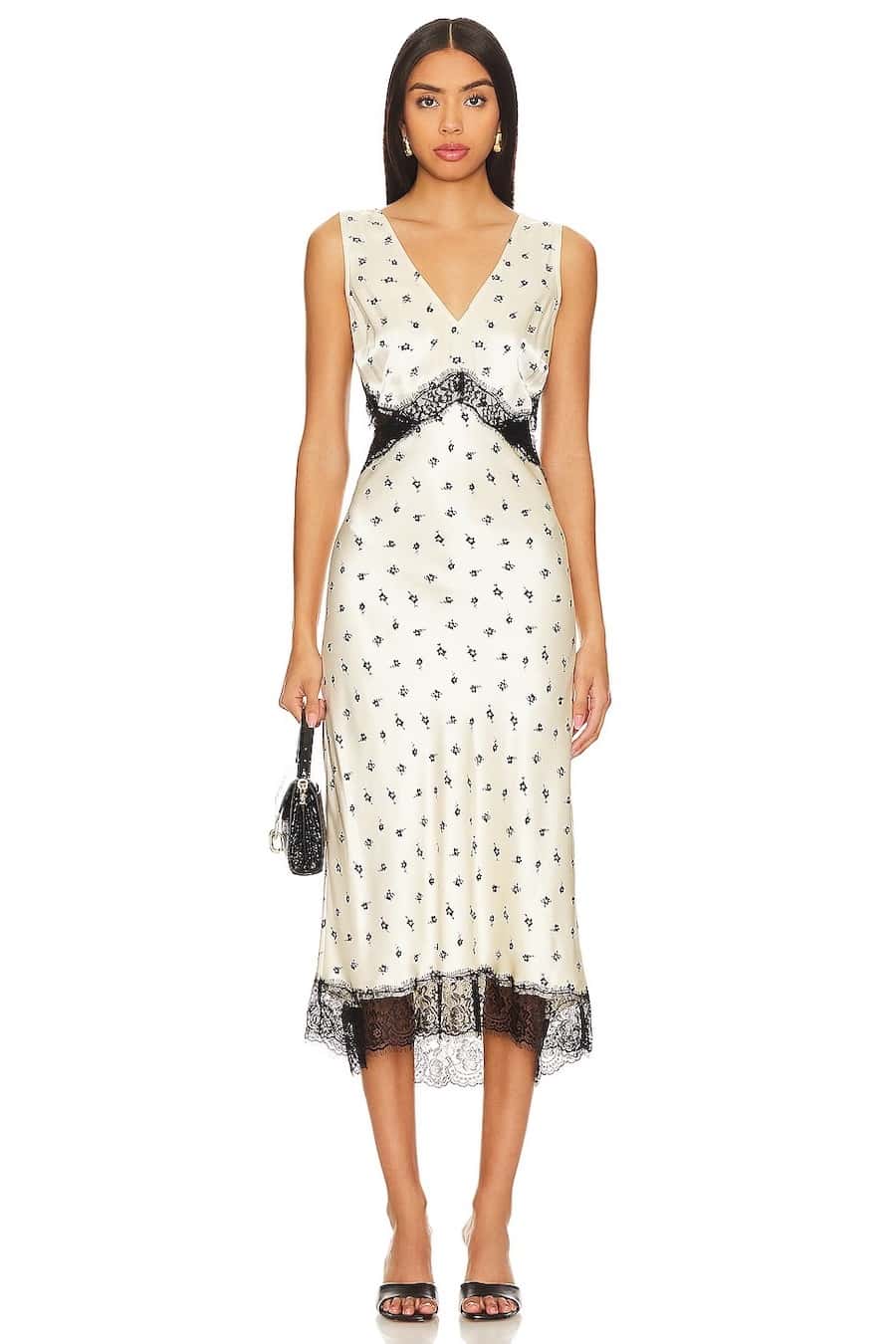 A woman wearing a white satin midi dress with a black pattern and black lace trim