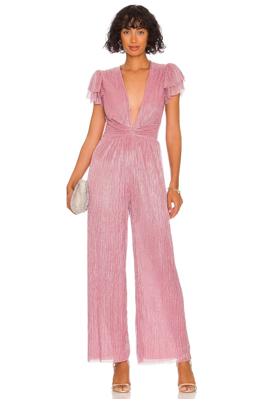 A woman wearing a pink jumpsuit with a deep v-neck, tiered ruffled short sleeves, and a wide-leg cut
