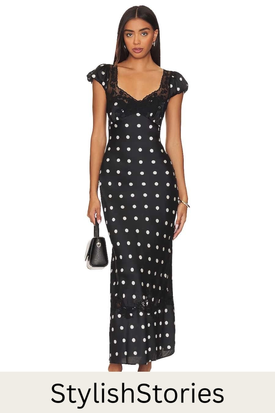 A woman wearing a black maxi dress with white polka dots with cap sleeves and a lace detail bodice