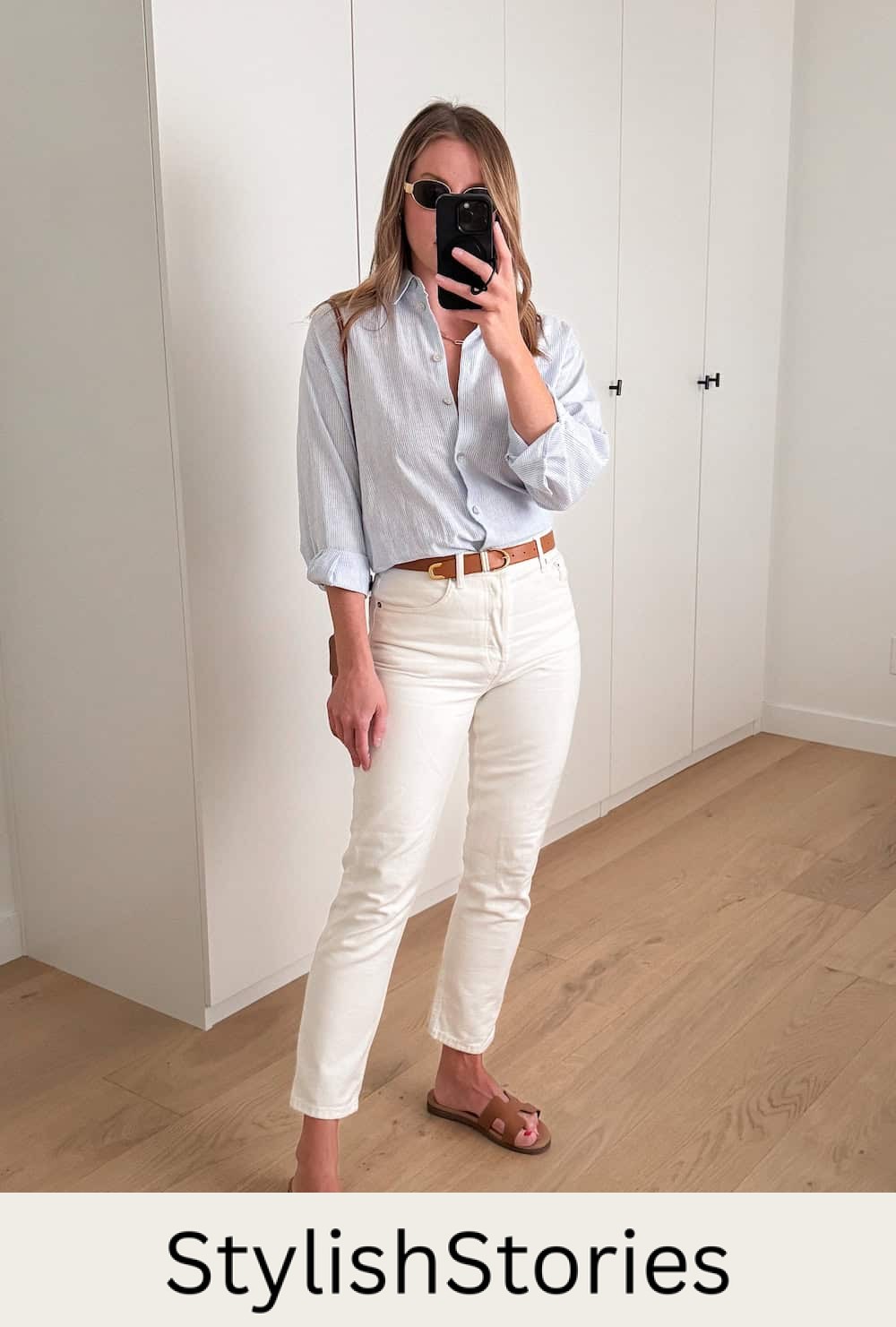 woman wearing a summer outfit with a blue striped button up shirt, off-white jeans and brown slide sandals