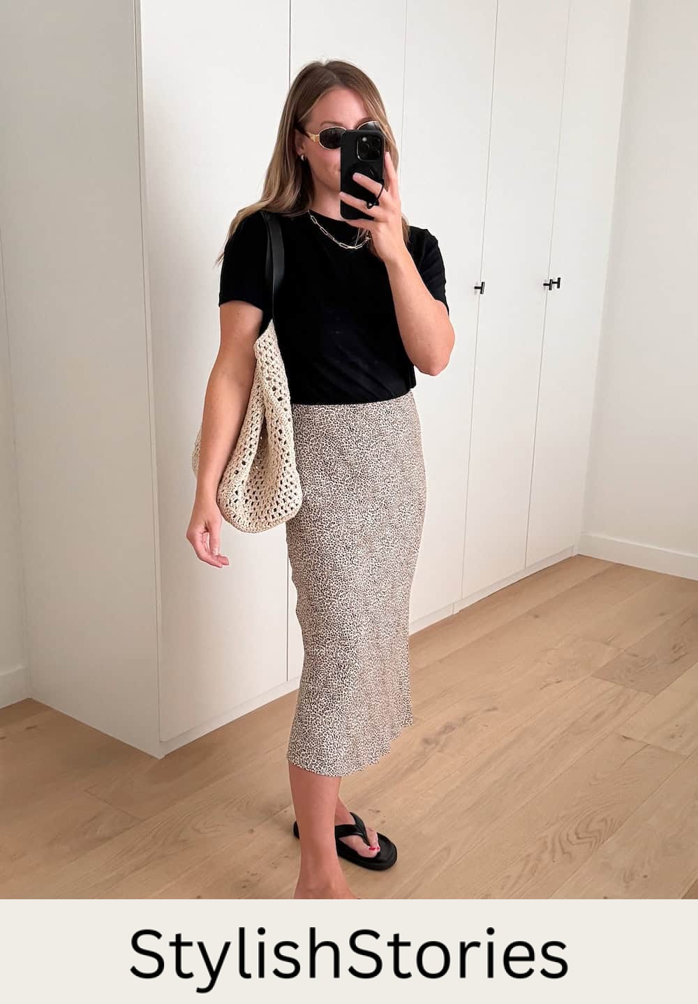 woman wearing a summer outfit with black t-shirt, leopard print slip skirt, and black chunky sandals
