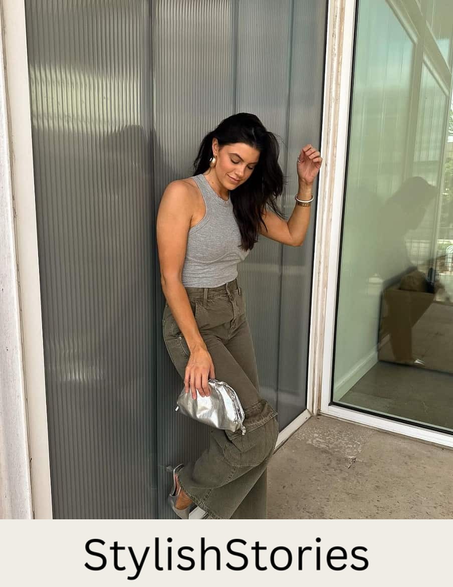A woman wearing khaki green cargo pants, a grey tank top, silver pumps, and a silver clutch