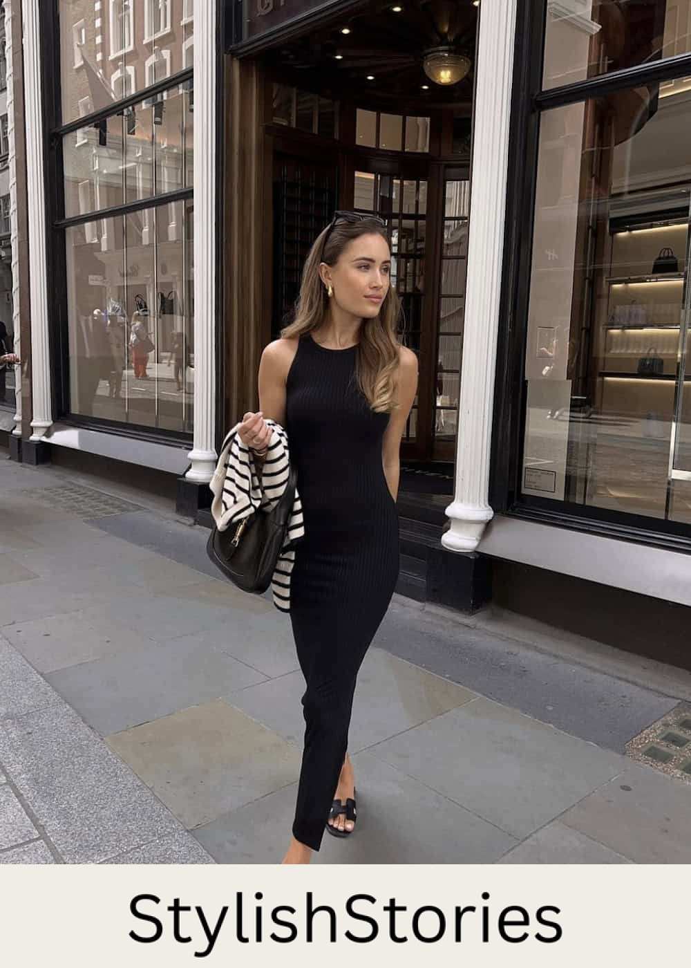 Woman wearing a tight, knit black midi dress with black sandals.