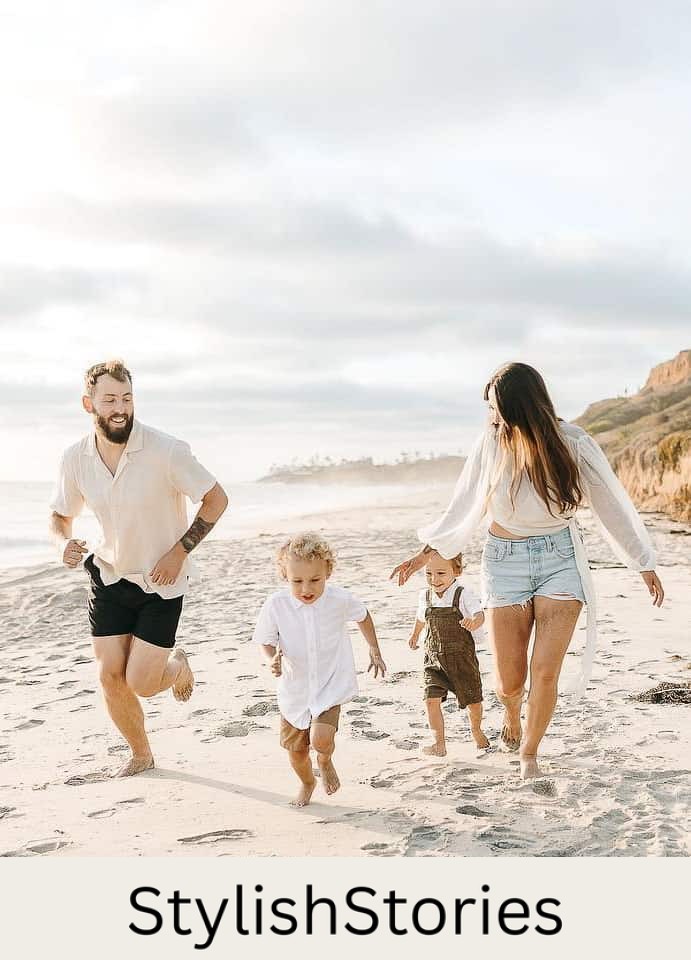 An image of a summer family photo with a family of four running on the beach, wearing white tops with shorts and overalls