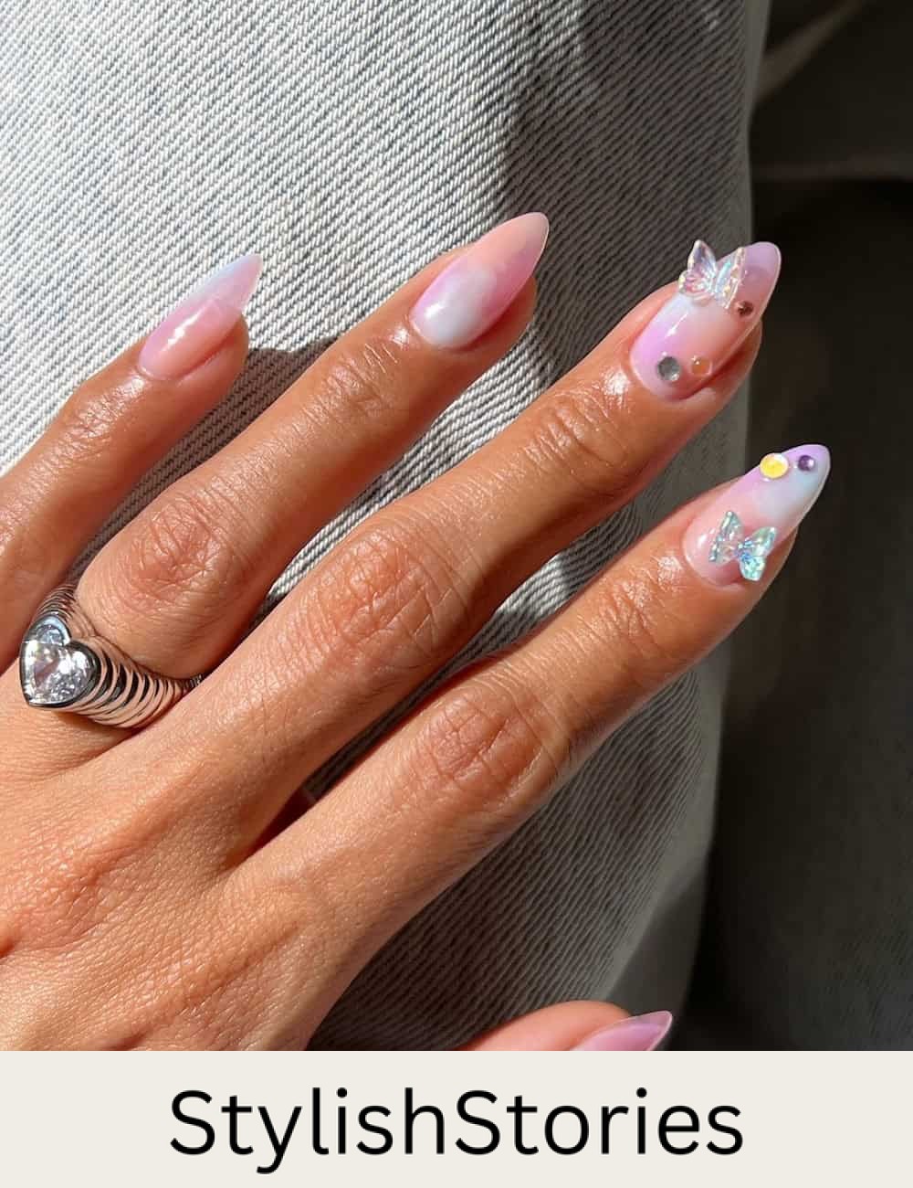 medium almond nails with soft pastel marbling, butterfly charms, and colorful crystal accents