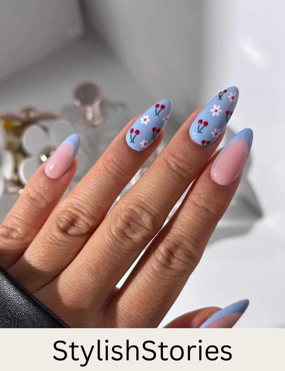 medium nude almond nails with baby blue tips and baby blue accent nails with cherry and floral nail art