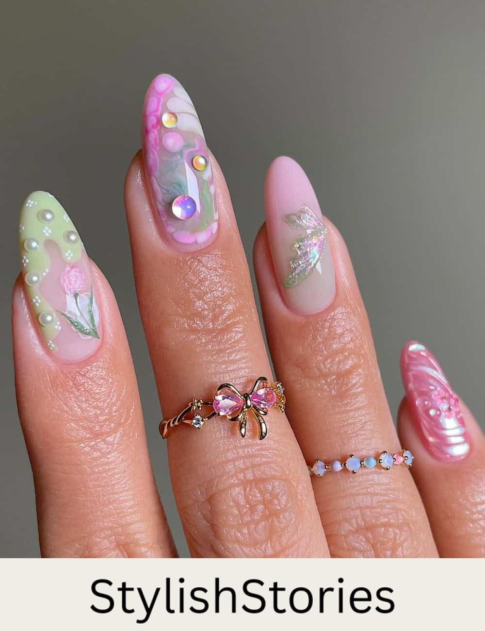 long almond nails with pink, purple, and green polish featuring 3D fairy nail art