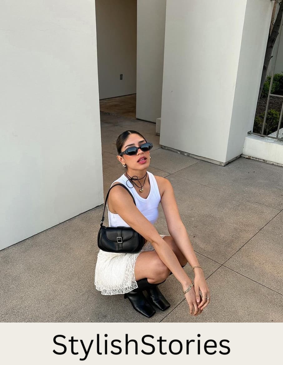 A woman wearing a lacy white mini skirt with a white tank, black boots, and a black shoulder bag