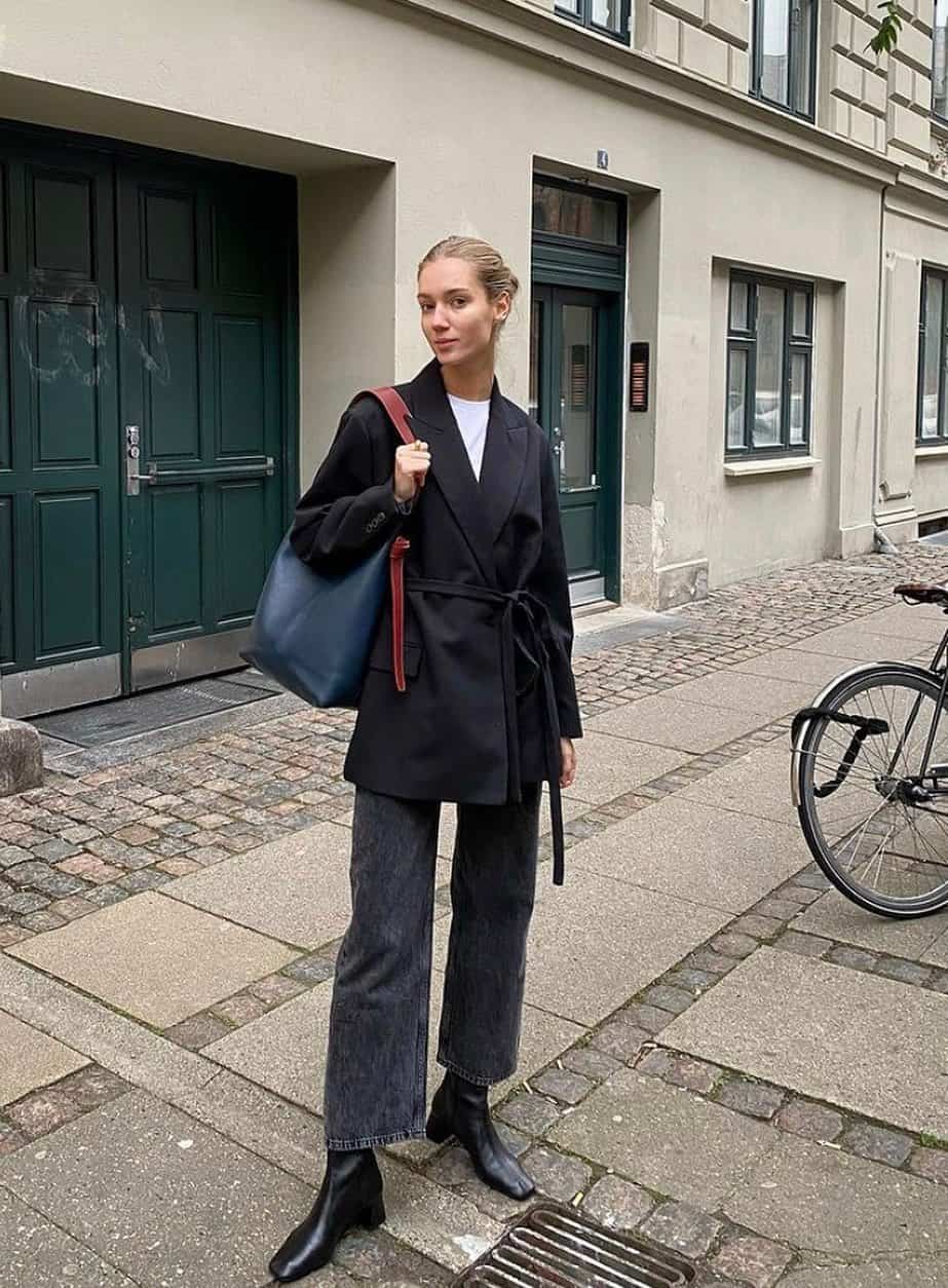 woman wearing a black trench coat with black loose-fit flared jeans and black ankle boots