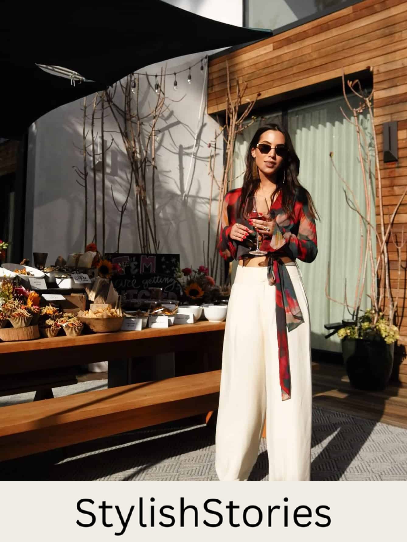 woman wearing a colorful blouse with wide leg palazzo pants holding a glass of wine