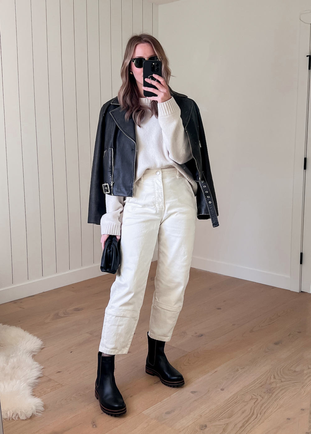 Christal wearing white jeans, black Chelsea boots a white sweater and a black leather jacket.