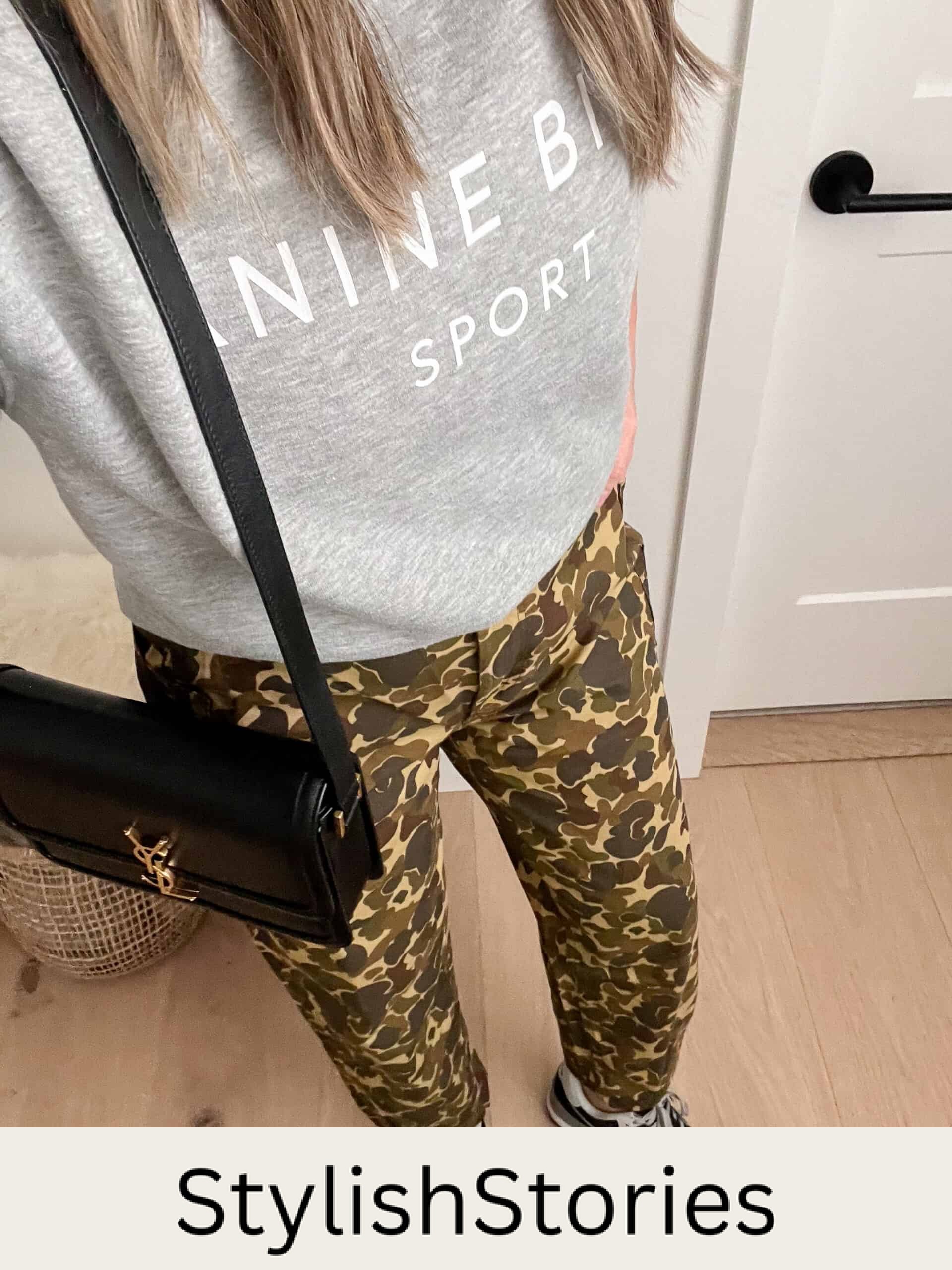 An overhead shot of a woman wearing camo pants with a grey sweatshirt and black trainers with a black crossbody bag