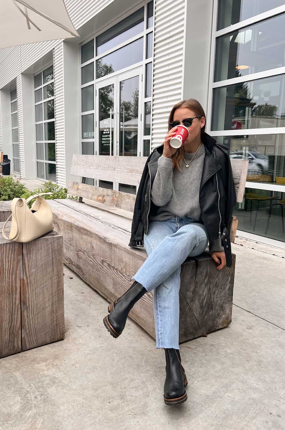 Christal wearing jeans, a grey sweater and a black leather jacket with black Chelsea boots.